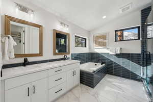 Full bath featuring vaulted ceiling, double vanity, a bath, a stall shower, and recessed lighting