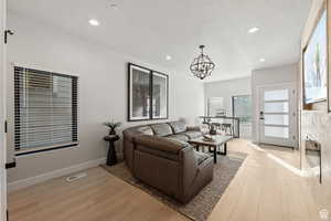 Living room featuring light wood-style floors, a chandelier, and a textured ceiling