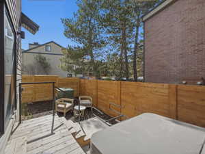 Outdoor deck with a covered spa, wood privacy fencing, and a separate seating area with natural ground cover