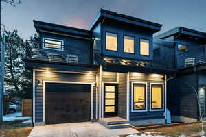 Contemporary house with a standing seam roof, an attached garage, and driveway