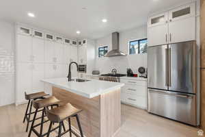 Kitchen with glass fronted cabinets, stainless steel appliances, white cabinets, an island with sink, and recessed lighting