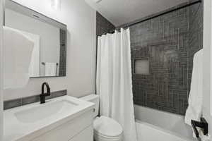 Full bath with vanity, shower / tub combo, and a textured ceiling