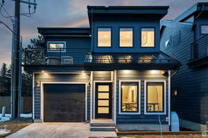Modern home featuring an attached garage, a balcony, driveway, and a metal roof