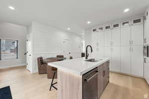 Two tone kitchen with two tone cabinetry, glass fronted cabinets, light wood finished floors, a kitchen bar, and stainless steel appliances