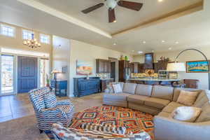 Living area with ceiling fan, a chandelier, and a tray ceiling