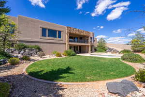 Back of property featuring a yard, stucco siding, and a balcony