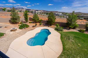 View of swimming pool with a fire pit, a fenced backyard, patio surround, a mountain view, and a residential view