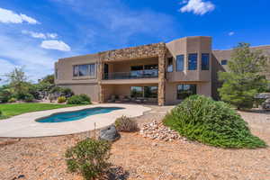 Back of property featuring an outdoor pool, a balcony, stucco siding, a patio, and stone siding