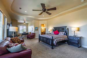 Bedroom featuring a tray ceiling, carpet, recessed lighting, a ceiling fan, and ensuite bath