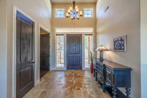 Foyer with inlaid floor details, healthy amount of natural light, a high ceiling, and suspended lighting