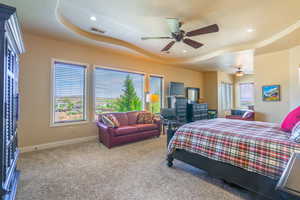 Bedroom with a tray ceiling, carpet flooring, multiple windows, recessed lighting, and ceiling fan