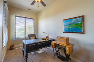 Carpeted home office featuring ceiling fan and baseboards
