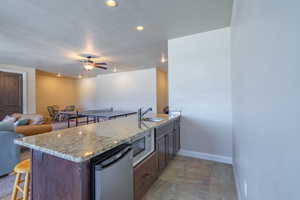 Kitchen featuring light stone counters, a peninsula, open floor plan, a breakfast bar area, and recessed lighting