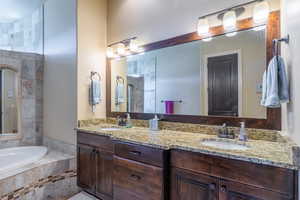 Bathroom featuring double vanity, a garden tub, and tiled shower