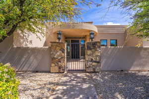Doorway to property with a gate, stucco siding, and stone siding