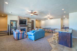 Living area featuring recessed lighting, ceiling fan, a fireplace, light colored carpet, and a textured ceiling
