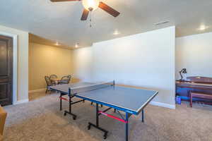 Recreation room featuring carpet, a ceiling fan, and a textured ceiling