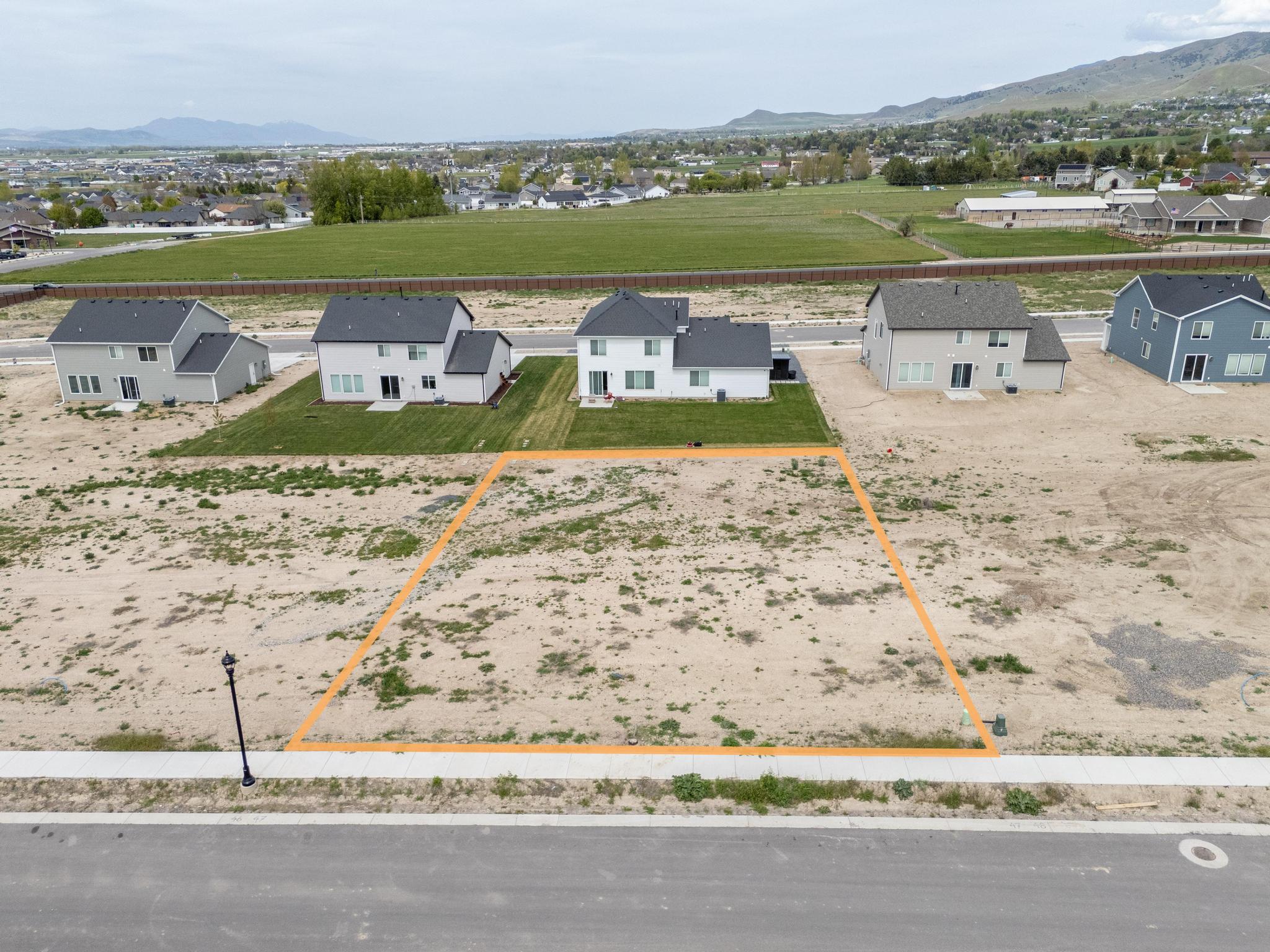 Aerial perspective of suburban area featuring a mountainous background and property parcel outlined