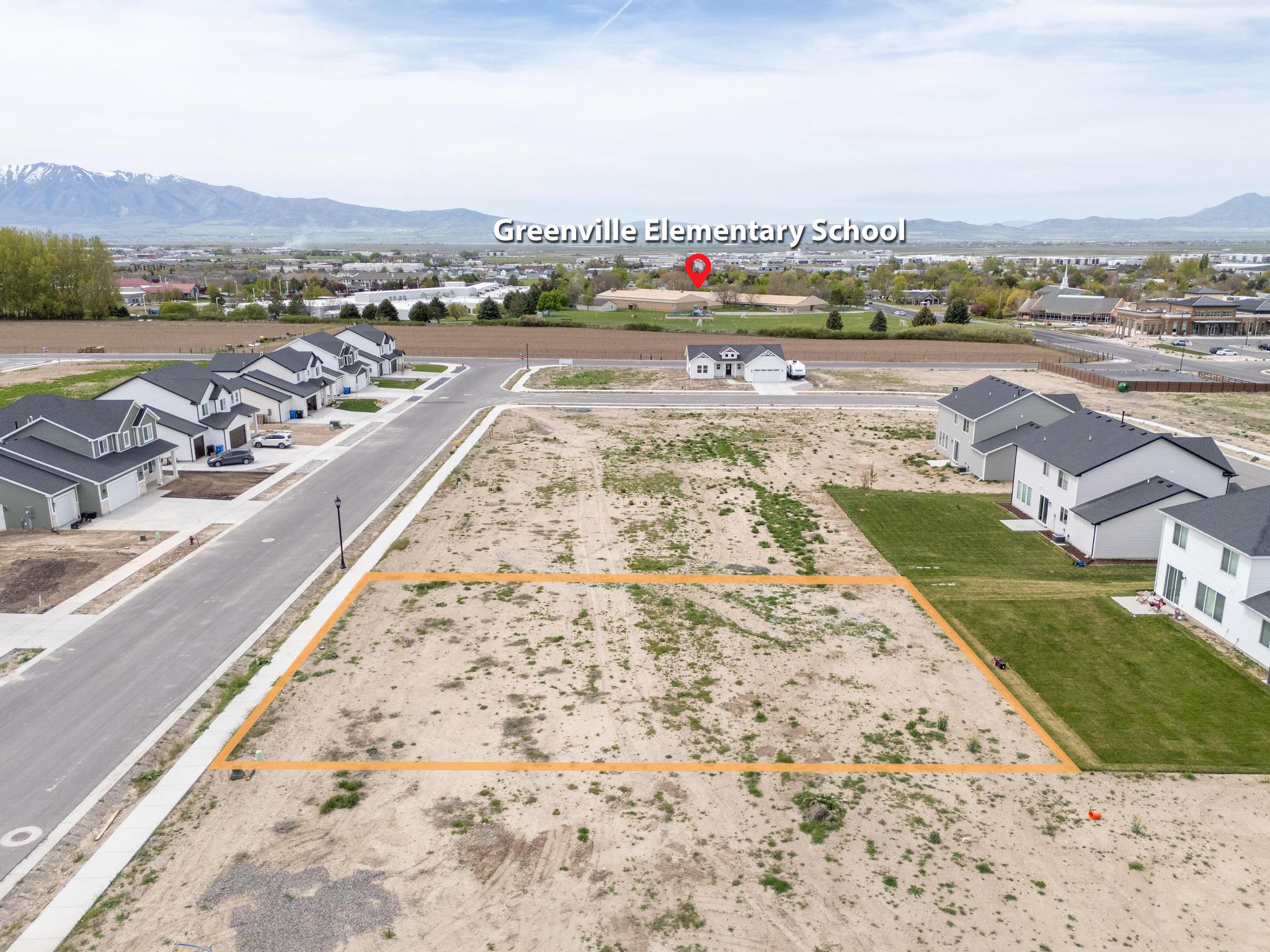 Aerial view of residential area featuring property boundaries highlighted and a mountainous background