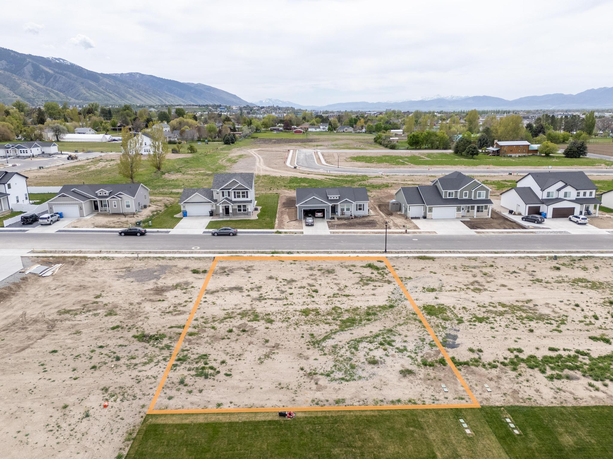 Aerial perspective of suburban area featuring property boundaries highlighted and a mountain backdrop
