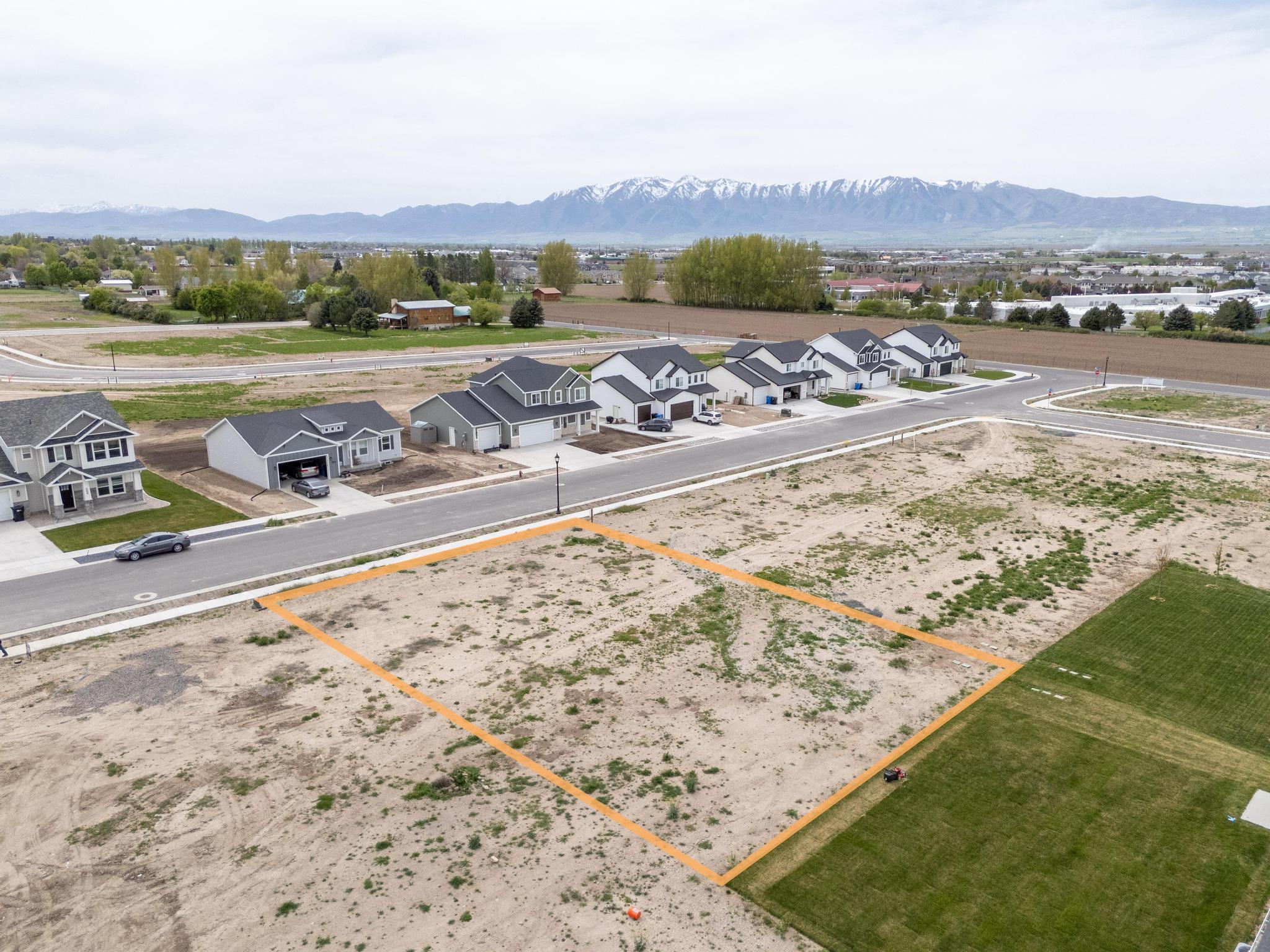Aerial view of residential area with property boundaries highlighted and a mountainous background