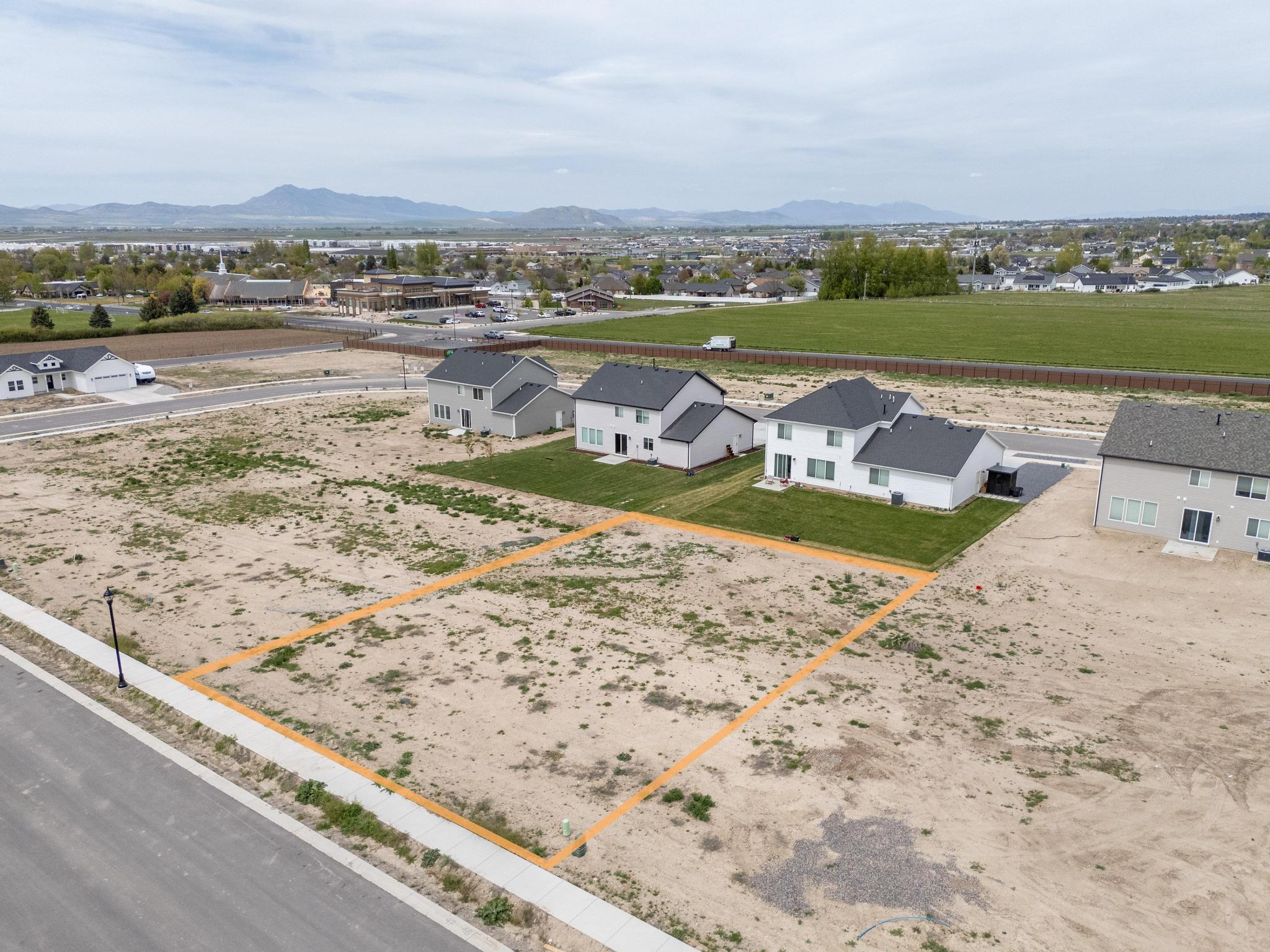 Aerial perspective of suburban area with property parcel outlined and mountains