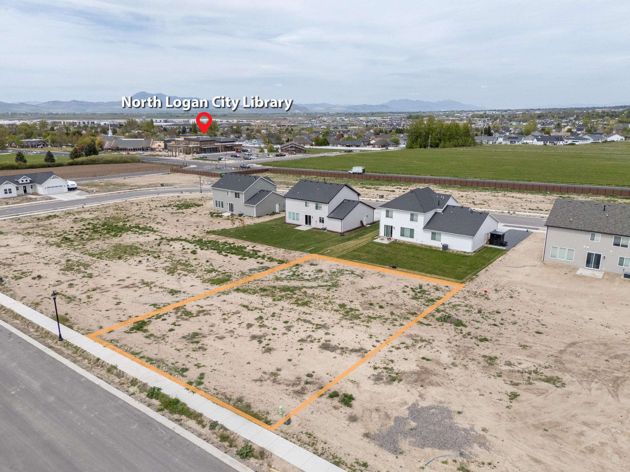 Aerial view of residential area with property boundaries highlighted and a mountainous background