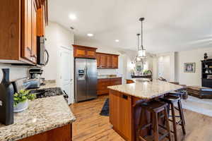 Kitchen with wood finish cabinetry, arched walkways, open floor plan, stainless steel appliances, and a kitchen bar