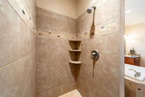 Bathroom featuring tiled shower, a garden tub, and vanity