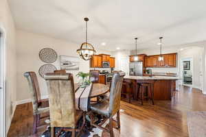 Dining room with dark wood-type flooring, arched walkways, and hanging lights