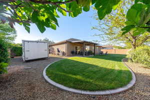 Back of property with a storage unit, a patio, stucco siding, and a fenced backyard