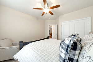 Carpeted bedroom with a ceiling fan and a closet