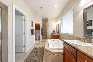 Full bathroom with two vanities, a tile shower, a whirlpool tub, and light tile patterned floors