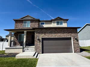View of front facade featuring covered porch, stone siding, driveway, stucco siding, and an attached garage