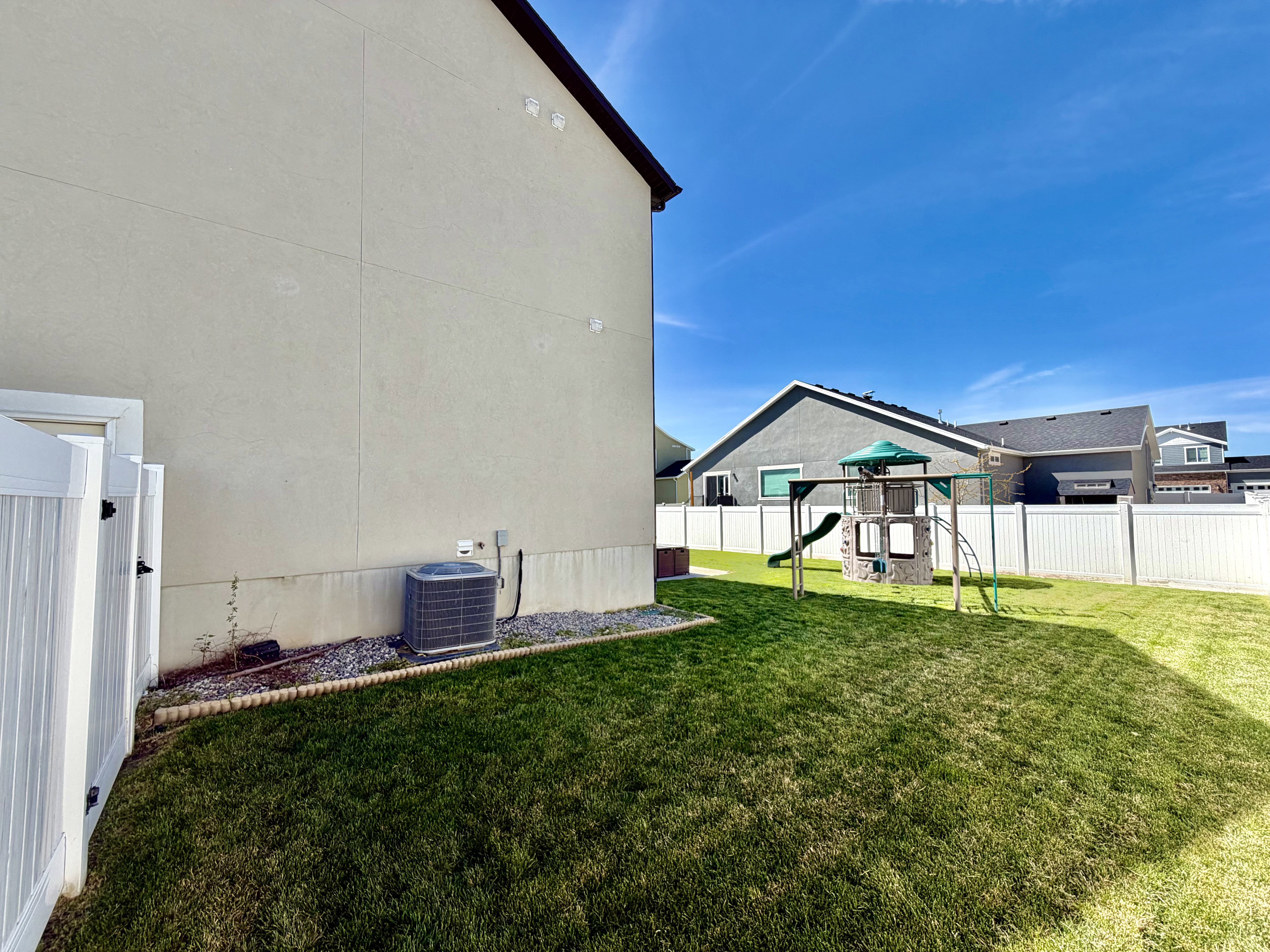 Fenced backyard featuring a playground