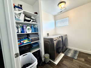 Laundry area featuring dark wood-type flooring, washing machine and clothes dryer, and a textured ceiling