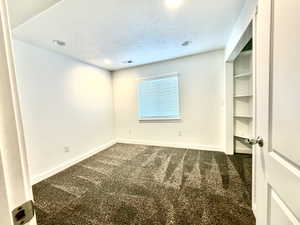 Unfurnished room with dark carpet, a textured ceiling, and recessed lighting