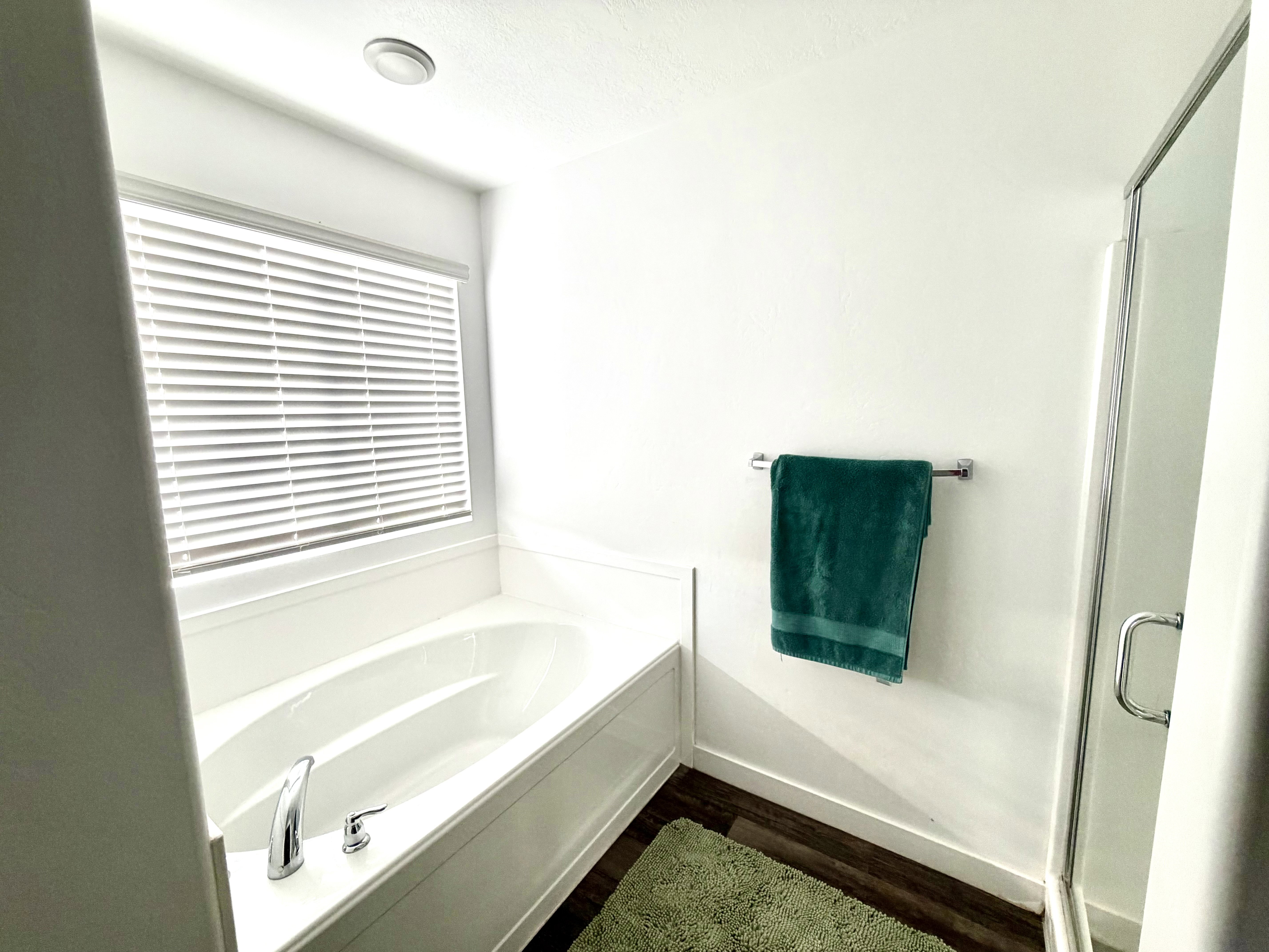 Full bath featuring a garden tub, a shower stall, dark wood-type flooring, and a textured ceiling