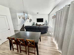 Dining space featuring a chandelier, light wood-type flooring, and a textured ceiling