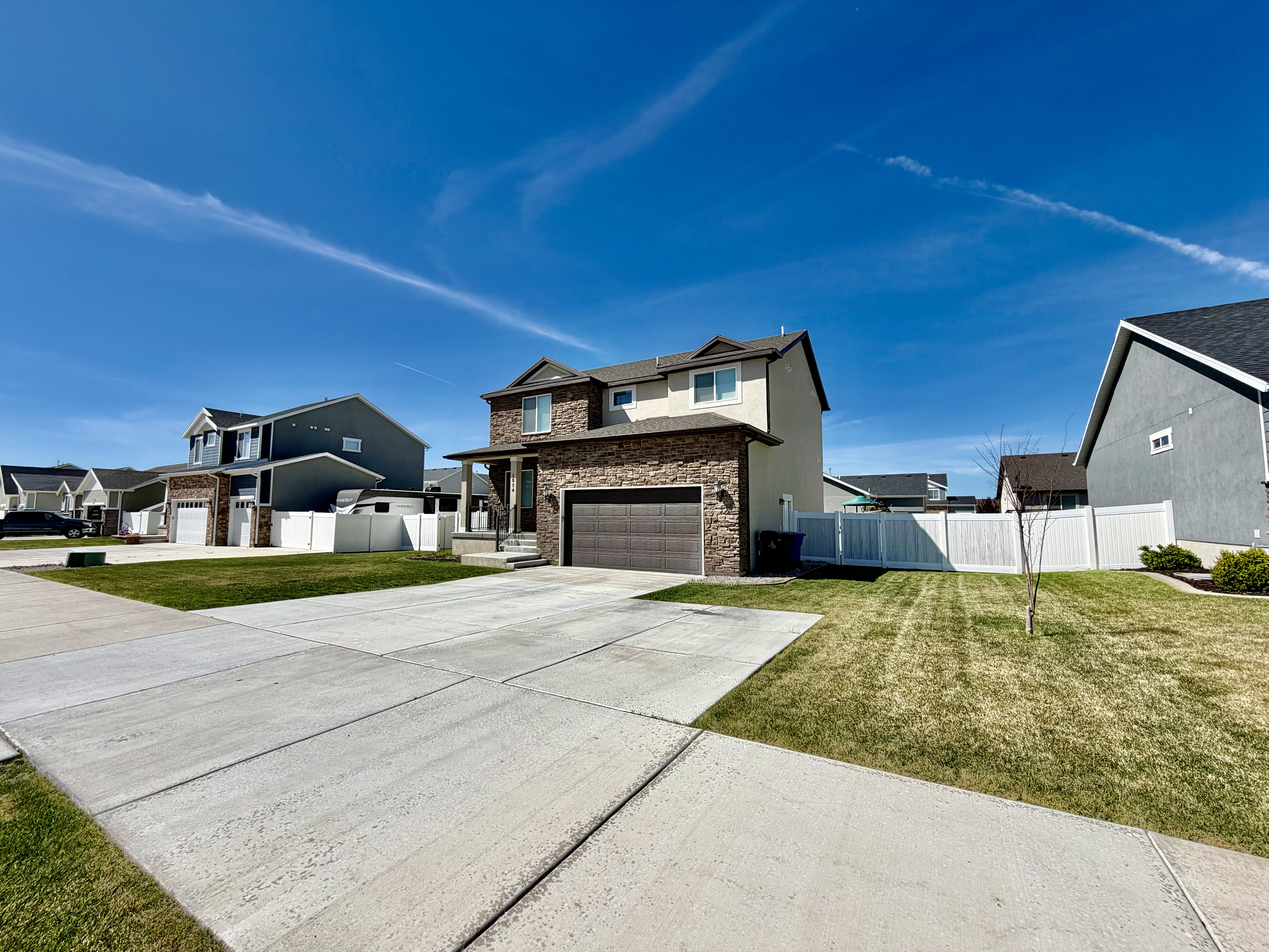 View of front of home with driveway, a residential view, stone siding, and an attached garage