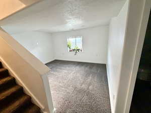 Unfurnished room with dark colored carpet and a textured ceiling