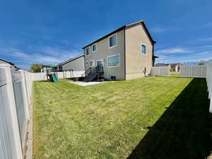 Rear view of property featuring a fenced backyard, a playground, stucco siding, and a patio area