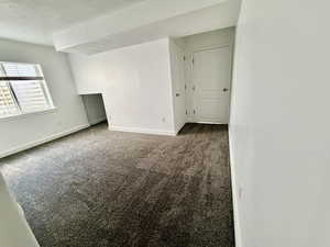 Empty room featuring dark carpet and baseboards