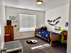 Bedroom featuring dark colored carpet and a textured ceiling