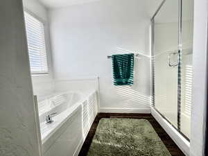 Bathroom featuring a bath, a stall shower, and dark wood finished floors