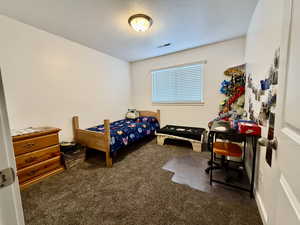 Bedroom featuring dark colored carpet and a textured ceiling