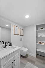 Half bathroom with light wood-type flooring and vanity