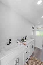Bathroom with double vanity, recessed lighting, dark wood finished floors, and a textured ceiling