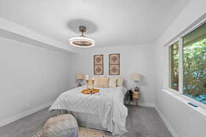 Bedroom with carpet floors, a textured ceiling, and ceiling fan