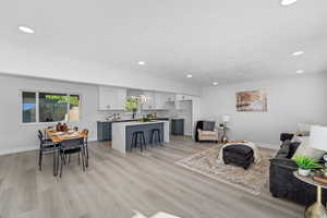 Living area with light wood finished floors and recessed lighting